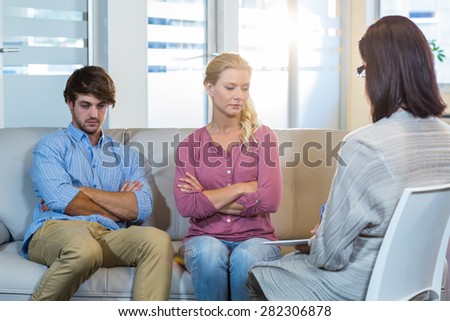 Unsmiling couple sitting on the couch in therapist office