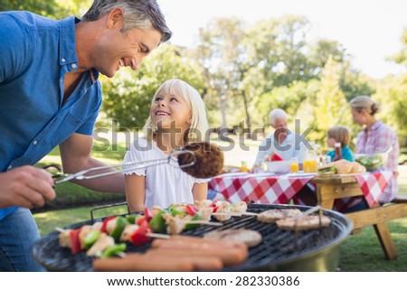Happy father doing barbecue with her daughter on a sunny day