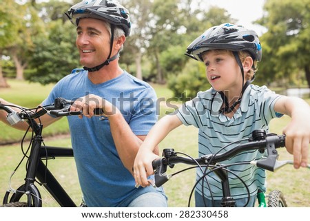 Happy father on a bike with his son on a sunny day