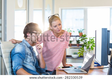 Smiling colleagues looking at laptop in the office