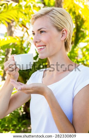 Attractive blonde woman holding mug outside on a sunny day