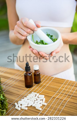 Happy blonde woman mixing herbs outside on a sunny day