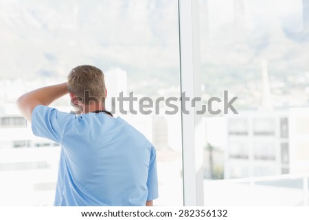 Male doctor looking through windows in hospital