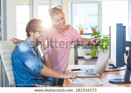 Smiling colleagues pointing at laptop in the office