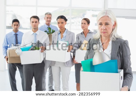Unhappy fired business people holding box in office