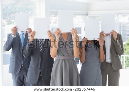 Business colleagues hiding their face with paper in the office