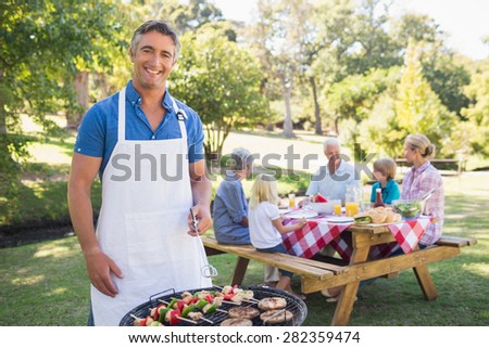 Happy man doing barbecue for his family in a sunny day