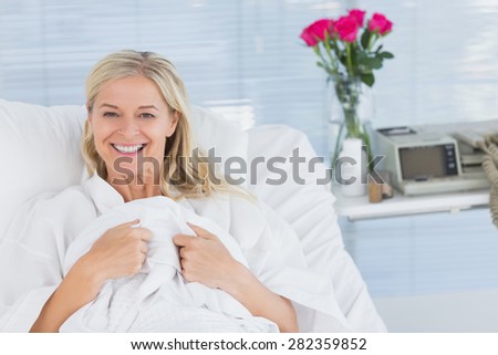 Smiling patient looking at camera on her bed in hospital