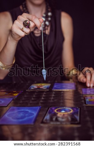 Fortune teller forecasting the future with pendulum on black background