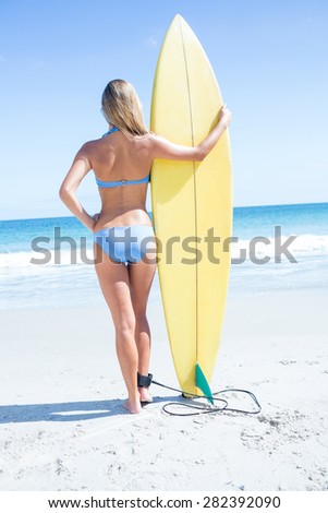 Pretty blonde woman holding surf board at the beach