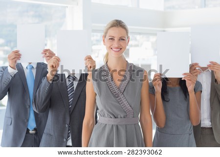 Business colleagues hiding their face with paper in the office