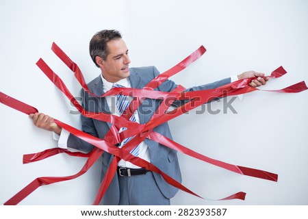 Businessman trapped by red tape on white background
