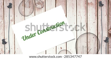 The word under construction and white card against wooden background with plugs