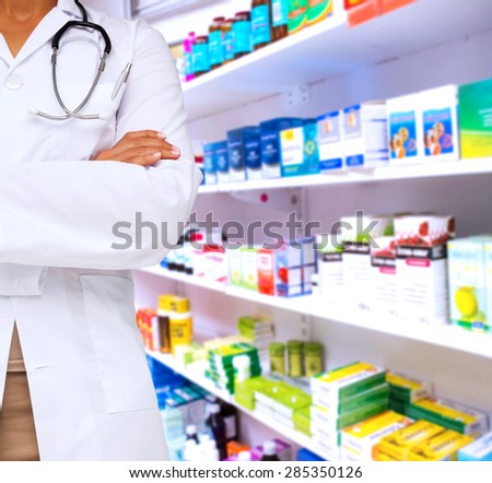 Mid section of a female doctor with skeleton model against close up of shelves of drugs