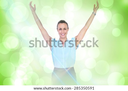 Businesswoman with arms raised against green abstract light spot design
