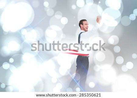 Businessman crossing the finish line against white glowing dots on grey