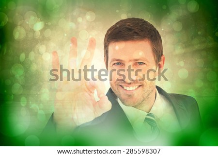 Businessman smiling and making ok sign against green abstract light spot design