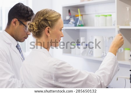 Concentrated scientists looking at beaker in laboratory