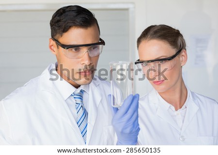Concentrated scientists looking at beaker in laboratory