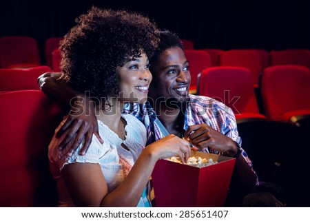 Happy young couple watching a film at the cinema