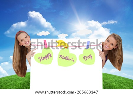 Portrait of wo long hair women back of a blank sign against green hill under blue sky