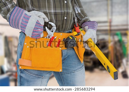 Handyman holding spirit level against workshop