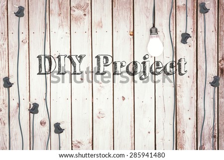 The word diy project against light bulb on wooden background