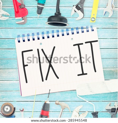 The word fix it against tools and notepad on wooden background