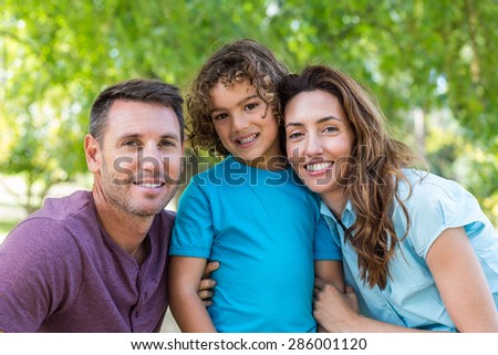 Happy family kissing at camera in the park on a sunny day
