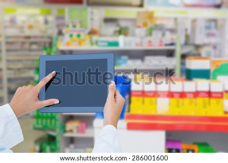 Doctor using tablet pc against close up of shelves of drugs