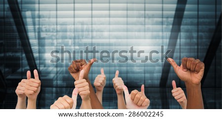 Hands giving thumbs up against room with large window looking on city