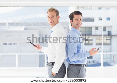 Two businessmen standing back to back in the office