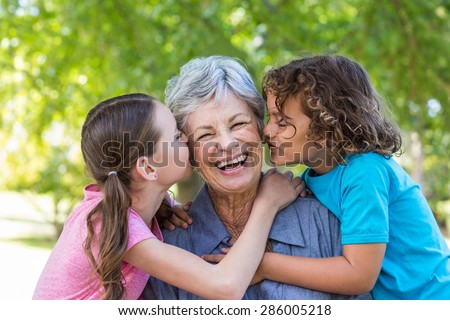 Extended family smiling and kissing in a park on a sunny day
