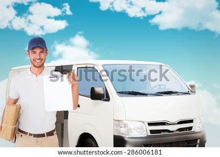 Happy delivery man holding cardboard box and clipboard against blue sky