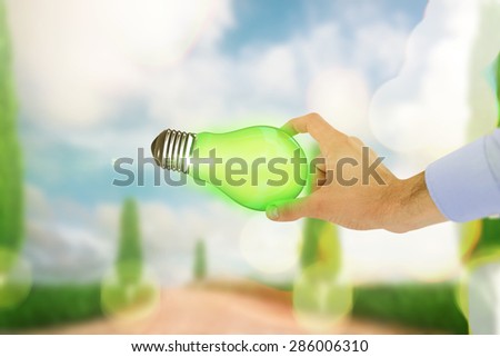 Businessman holding hand out in presentation against road leading out to the horizon