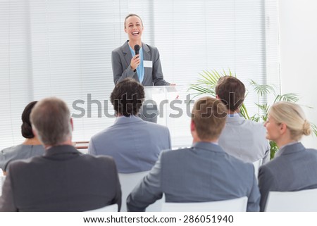 Pretty businesswoman talking in microphone during conference in meeting room