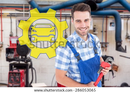 Confident young male repairman holding monkey wrench against workshop