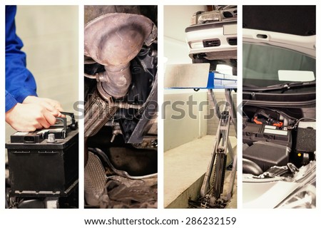 Mechanic changing car battery against mechanic under car in garage