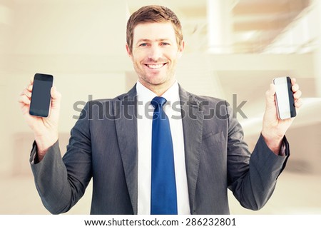 Businessman holding two smart phones against airport terminal