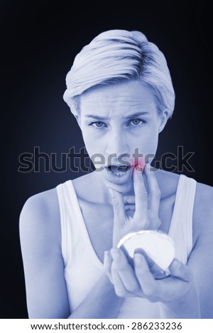 Shocking woman with mirror looking at camera against blue background with vignette