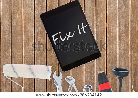 The word fix it against tools and tablet on wooden background