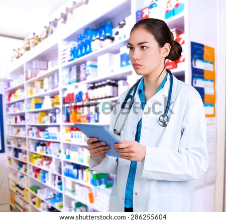 Young doctor standing with tablet pc against close up of shelves of drugs