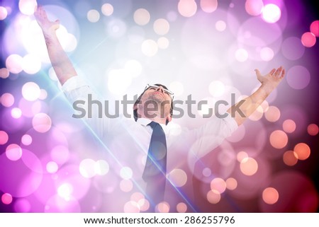 Handsome businessman cheering with arms up against light glowing dots on purple