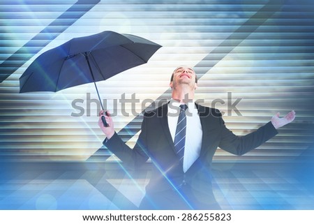 Businessman sheltering under black umbrella testing against window overlooking city