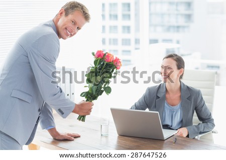 Businessman offering flowers to his colleague in an office