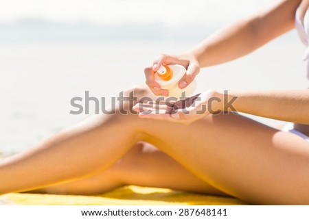 Close up view of Pretty blonde woman putting sun tan lotion on her hand at the beach
