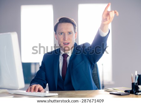 Angry businessman pointing and shouting in his office