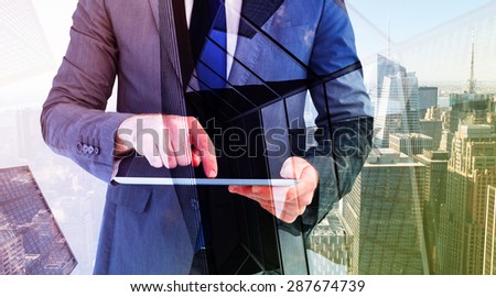 Businessman using his tablet pc against skyscraper