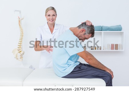 Doctor stretching a man back in medical office