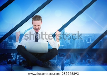 Businessman using laptop and cheering against room with large window looking on city
